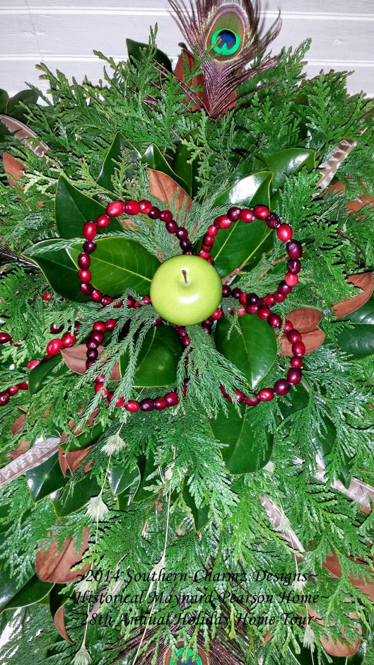 Cranberry flower petals with a large green apple center nestled into gorgeous boughs of cedar and magnolia evergreens to Celebrate Christmas!